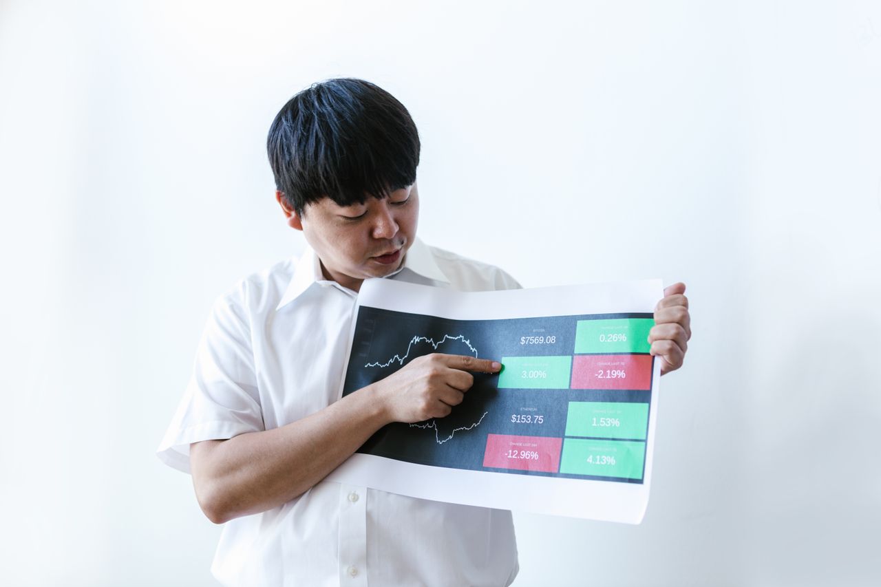 hero-img Asian businessman in white shirt presenting cryptocurrency market data on chart.